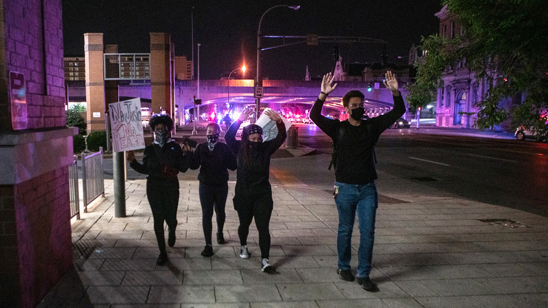 Protesters in Louisville, Ky., on Sept. 23, 2020, walk away from police with their hands up after two police officers were shot during a protest after a grand jury considering the March killing of Breonna Taylor, a Black medical worker, in her home in Louisville, voted to indict one of three White police officers for wanton endangerment.