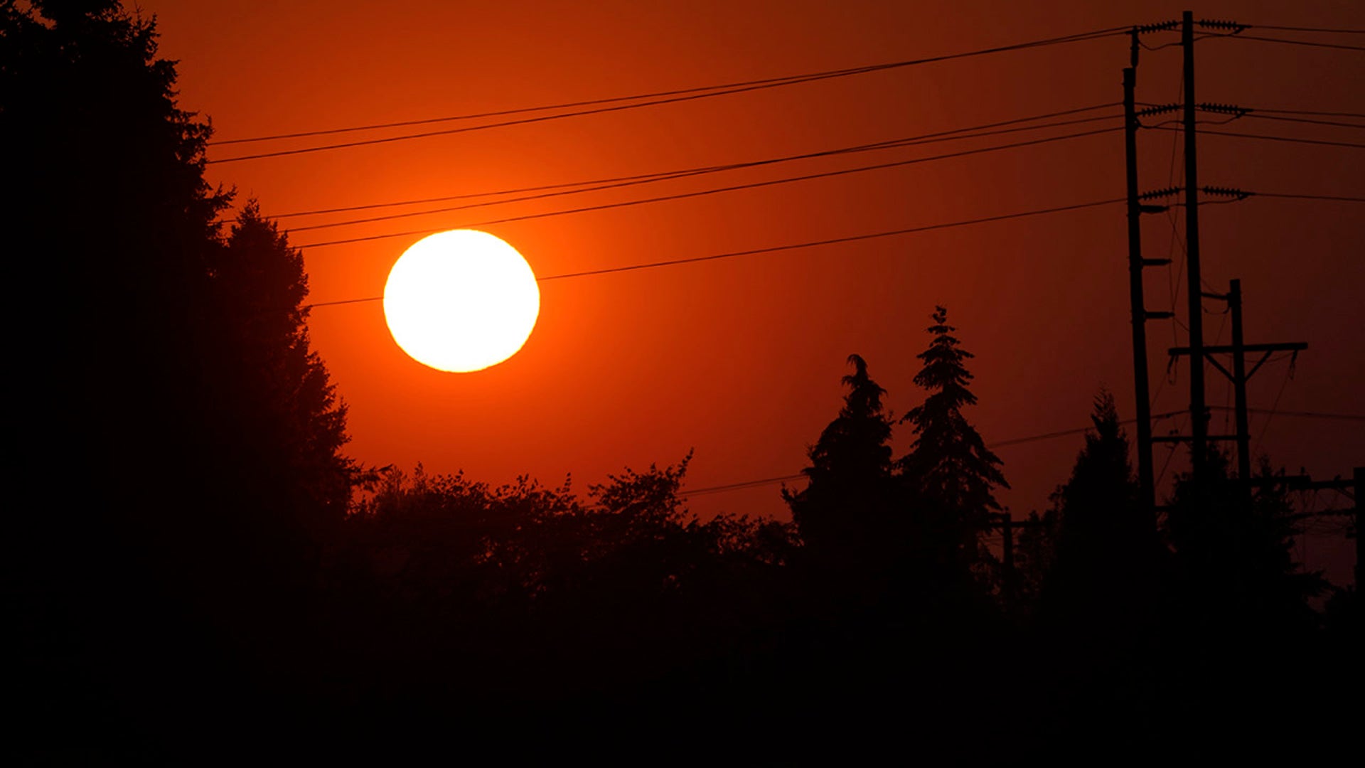 The sun is seen against a sky turned orange with smoke from wildfires as it sets, Tuesday, Sept. 8, 2020, near Sumner, Wash., south of Seattle.
