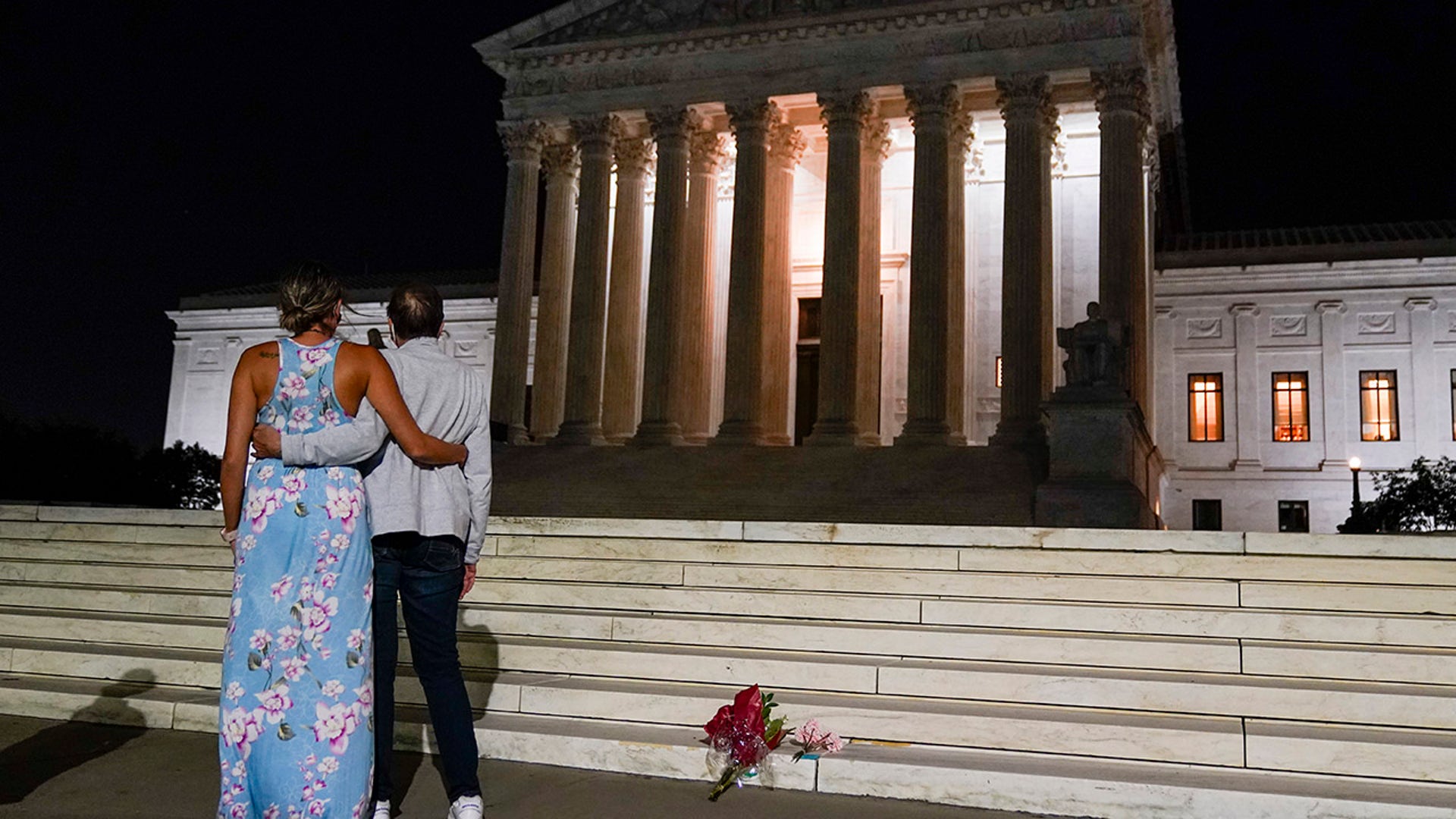 A couple pauses outside the Supreme Court Friday, Sept. 18, 2020, in Washington, after the Supreme Court announced that Supreme Court Justice Ruth Bader Ginsburg has died of metastatic pancreatic cancer at age 87. (AP Photo/Alex Brandon)