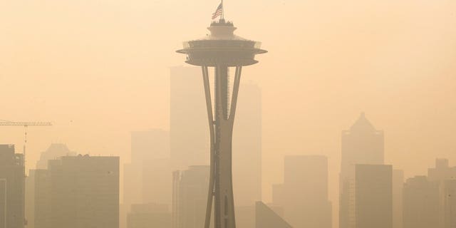 FILE - In this Sept. 11, 2020, file photo, an American flag on top the Space Needle was lowered to half-staff today by the Seattle Fire Department to remember those who lost their lives on 9/11, Friday, Sept. 11, 2020. Thick smoke from wildfires burning across Washington, Oregon and California makes seeing the Space Needle and downtown Seattle nearly impossible in this view from Queen Anne Hill. (Mike Siegel/The Seattle Times via AP, File)