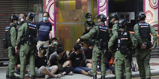 People, sitting on the ground, are arrested by police officers at a downtown street in Hong Kong Sunday, Sept. 6, 2020. About 30 people were arrested Sunday at protests against the government's decision to postpone elections for Hong Kong's legislature, police and a news report said. (AP Photo/Vincent Yu)