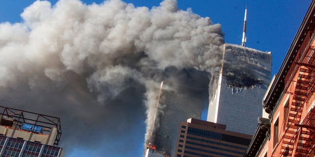 FILE - In this Sept. 11, 2001, file photo, smoke rises from the burning twin towers of the World Trade Center after hijacked planes crashed into the towers, in New York City. The coronavirus pandemic has reshaped how the U.S. is observing the anniversary of 9/11. The terror attacks' 19th anniversary will be marked Friday, Sept. 11, 2020, by dueling ceremonies at the Sept. 11 memorial plaza and a corner nearby in New York. (AP Photo/Richard Drew, File)