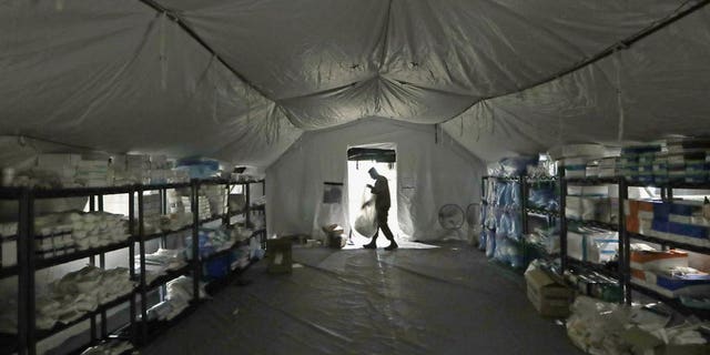 In this March 31, photo a U.S. Army soldier walks inside a mobile surgical unit being set up by soldiers from Fort Carson, Col., and Joint Base Lewis-McChord (JBLM) as part of a field hospital inside CenturyLink Field Event Center, in Seattle. Military suicides have increased by as much as 20% this year compared to the same period last year, and some incidents of violent behavior have spiked, as service members struggle with isolation and other impacts of COVID-19 added to the pressures of war-zone deployments and responding to national disasters and civil unrest. (AP Photo/Elaine Thompson, File)