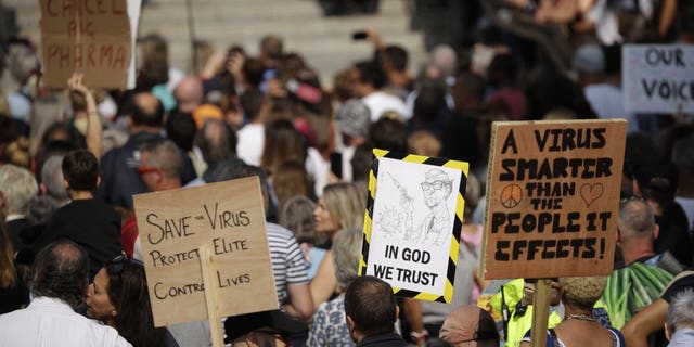 People hold placards including one portraying Bill Gates as they take part in a "Resist and Act for Freedom" protest against a mandatory coronavirus vaccine, wearing masks, social distancing and a second lockdown, in Trafalgar Square, London, Saturday, Sept. 19, 2020. (AP Photo/Matt Dunham)