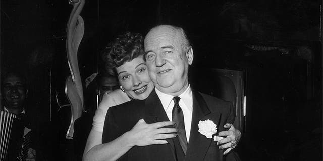 Circa 1953: American actor Lucille Ball (1911-1989) hugs American actor William Frawley (1887-1966) as she stands behind him during the surprise party for her 13th wedding anniversary to Desi Arnaz, held at Larry Finley's restaurant on Sunset Strip, Los Angeles, Calif.