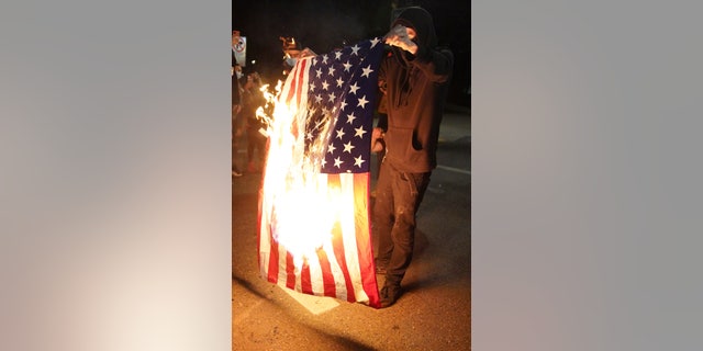 A protester burns an American flag while rallying at the Mark O. Hatfield United States Courthouse on Saturday, Sept. 26, 2020, in Portland, Ore. The rally came as Portland has seen nearly nightly protests since the police killing of George Floyd in late May. (AP Photo/Allison Dinner)