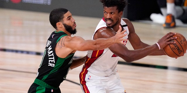The Boston Celtics' Jayson Tatum, left, defends against the Miami Heat's Jimmy Butler during the second half of an NBA Eastern Conference final playoff basketball game Friday, Sept. 25, 2020, in Lake Buena Vista, Fla. (AP Photo/Mark J. Terrill)