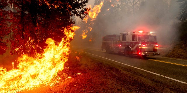 In this Sept. 7, file photo a firetruck drives along state Highway 168 while battling the Creek Fire in the Shaver Lake community of Fresno County, Calif. 