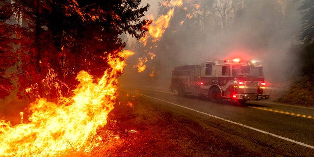 In this Sept. 7, file photo a firetruck drives along state Highway 168 while battling the Creek Fire in the Shaver Lake community of Fresno County, Calif. 