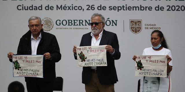 Mexico's President Andres Manuel Lopez Obrador, links, and Deputy Interior Secretary Alejandro Encinas, sentrum, stand with Maria Martinez, mother of Miguel Angel Hernandez Martinez, as they hold cloths embroidered by mothers of some of 43 missing students from the Rural Normal School of Ayotzinapa, with a message reading in Spanish; "For the 43 and thousands of others, don't fail us, Ayotzinapa," following a presentation on the ongoing investigation on the sixth anniversary of the students enforced disappearance, at the National Palace in Mexico City, Saterdag, Sept.. 26, 2020.(AP Photo/Rebecca Blackwell)