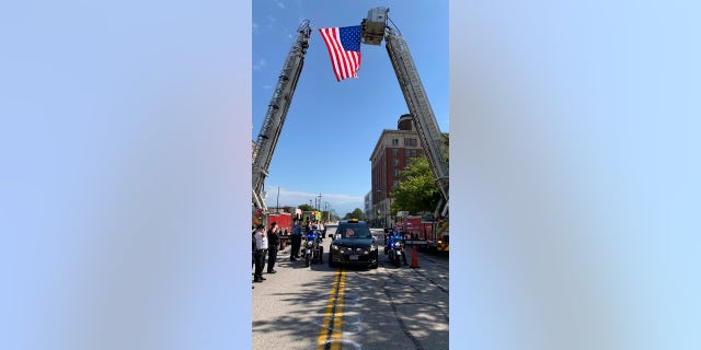 In this photo provided by the Cleveland Division of Fire, a hearse bearing the body of Detective James Skernivitz passes under an arch made by two Cleveland Division of Fire fire engines as it proceeds to the funeral home under police escort Saturday, Sept. 5, 2020. (Lt. Mike Norman/Cleveland Division of Fire via AP)