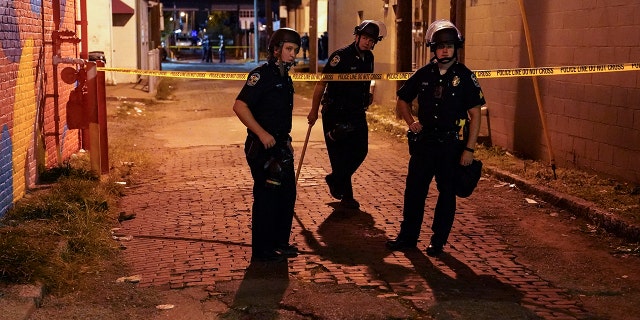 Police survey an area after a police officer was shot, Wednesday, Sept. 23, 2020, in Louisville, Ky. (AP Photo/John Minchillo)