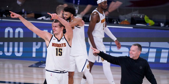 Denver Nuggets center Nikola Jokic (15) and Denver Nuggets head coach Michael Malone, right, celebrates their win over the Los Angeles Clippers in an NBA conference semifinal playoff basketball game Tuesday, Sept. 15, 2020, in Lake Buena Vista, Fla. (AP Photo/Mark J. Terrill)