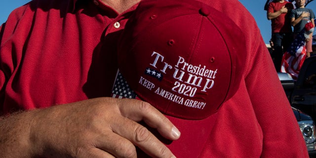 A man takes off his hat in prayer during a rally in support of President Donald Trump on Aug. 29, in Clackamas, Ore. (AP Photo/Paula Bronstein)