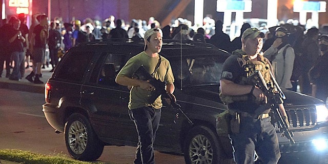 Kyle Rittenhouse, left, with backwards cap, walks along Sheridan Road in Kenosha, Wis., with another armed civilian. (Adam Rogan/The Journal Times via AP, File)