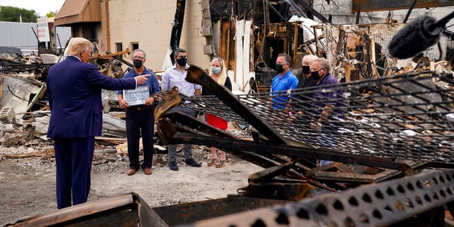 President Donald Trump talks to business owners Tuesday, Sept. 1, 2020, as he tours an area damaged during demonstrations after a police officer shot Jacob Blake in Kenosha, Wis. (AP Photo/Evan Vucci)