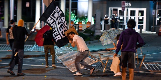 Protesters tear down the barricades in front of the Public Safety Building in Rochester, N.Y., Thursday, Sept. 3, 2020. Seven police officers involved in the suffocation death of Daniel Prude in Rochester were suspended Thursday by the city's mayor, who said she was misled for months about the circumstances of the fatal encounter. (AP Photo/Adrian Kraus)