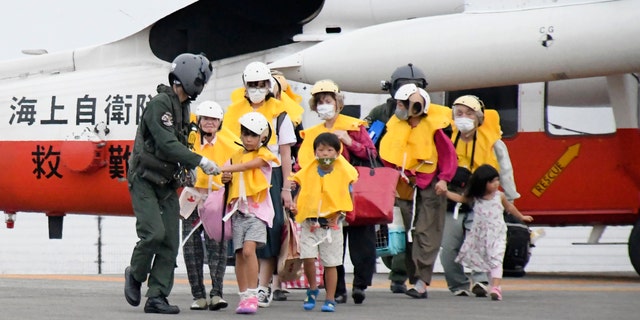 People arrive at a heliport in Kagoshima, in southern Japan, on Friday, Sept. 4, 2020, to take refuge ahead of a powerful typhoon. (Kyodo News via AP)