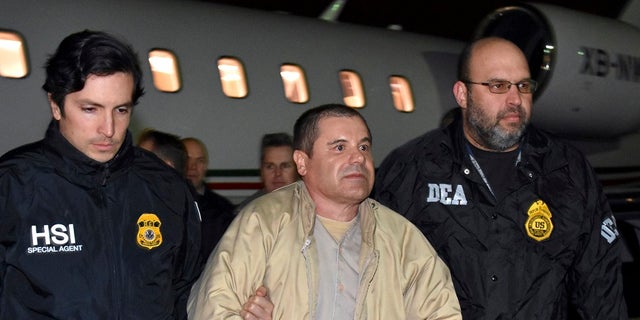 Autoriteiten begeleiden Mexicaanse drugsbaron Joaquin "El Chapo" Guzman, midden, vanuit een vliegtuig in Ronkonkoma, NY  