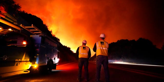 Pacific Gas and Electric workers stand along Highway 168 as the Creek Fire advances Tuesday, Sept. 8, 2020, near Alder Springs, Calif. (AP Photo/Marcio Jose Sanchez)