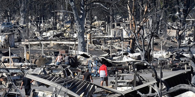 Men walk through the fire-ravaged Coleman Creek Estates mobile home park in Phoenix, Ore., on Wednesday, Sept. 9, 2020. The Almeda Fire that burned through the towns of Phoenix and Talent in southern Oregon destroyed approximately 600 homes, according to the Federal Emergency Management Agency. (Scott Stoddard/Grants Pass Daily Courier via AP)