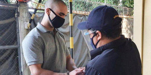 In this photo provided by the Philippines' Bureau of Immigration, U.S. Marine Lance Cpl. Joseph Scott Pemberton has handcuffs placed before leaving Camp Aguinaldo on his way to the airport in Quezon city, Philippines, Sunday, Sept. 13, 2020. (Bureau of Immigration via AP)