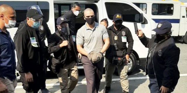 In this photo provided by the Philippines' Bureau of Immigration Public Information Office, (PIO), U.S. Marine Lance Cpl. Joseph Scott Pemberton, center, is escorted as he arrives at the airport before boarding a U.S. military plane in Manila, Philippines, Sunday, Sept. 13, 2020. (Bureau of Immigration PIO via AP)