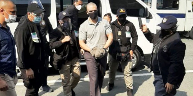 In this photo provided by the Philippines' Bureau of Immigration Public Information Office, (PIO), U.S. Marine Lance Cpl. Joseph Scott Pemberton, center, is escorted as he arrives at the airport before boarding a U.S. military plane in Manila, Philippines, Sunday, Sept. 13, 2020. (Bureau of Immigration PIO via AP)
