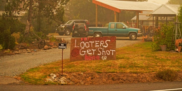 A sign warns that "Looters get shot" at a home near the Riverside Fire, Sunday, Sept. 13, 2020, near Molalla, Ore. (AP Photo/John Locher)