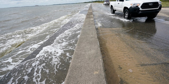 Waters from the Gulf of Mexico poor onto a local road, Monday, Sept. 14, 2020, in Waveland, Miss. (AP Photo/Gerald Herbrt)