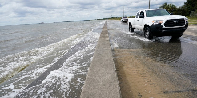 Waters from the Gulf of Mexico poor onto a local road, Monday, Sept. 14, 2020, in Waveland, Miss. (AP Photo/Gerald Herbrt)