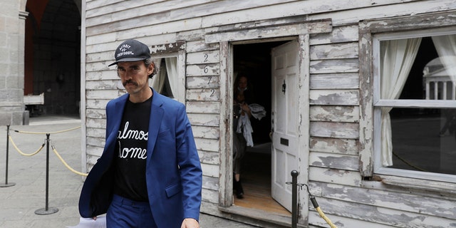 Artist Ryan Mendoza walks in front of the house of U.S. civil rights campaigner Rosa Parks, which he rebuilt for public display, in Naples, Italy, Tuesday, Sept. 15, 2020. The rundown, paint-chipped Detroit house where Parks took refuge after her famous bus boycott is on display in a setting that couldn't be more incongruous: the imposing central courtyard of the 18th century Royal Palace. (AP Photo/Gregorio Borgia)