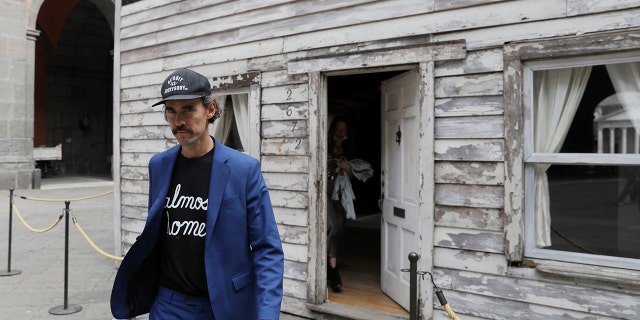 Artist Ryan Mendoza walks in front of the house of U.S. civil rights campaigner Rosa Parks, which he rebuilt for public display, in Naples, Italy, Tuesday, Sept. 15, 2020. The rundown, paint-chipped Detroit house where Parks took refuge after her famous bus boycott is on display in a setting that couldn't be more incongruous: the imposing central courtyard of the 18th century Royal Palace. (AP Photo/Gregorio Borgia)