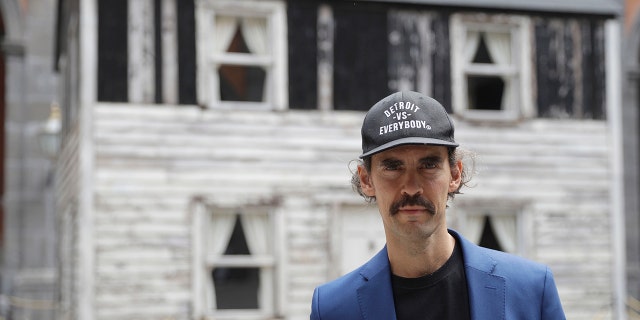 Artist Ryan Mendoza poses for photographers in front of the house of U.S. civil rights campaigner Rosa Parks, which he rebuilt for public display, in Naples, Italy, Tuesday, Sept. 15, 2020. The rundown, paint-chipped Detroit house where Parks took refuge after her famous bus boycott is on display in a setting that couldn't be more incongruous: the imposing central courtyard of the 18th century Royal Palace. (AP Photo/Gregorio Borgia)