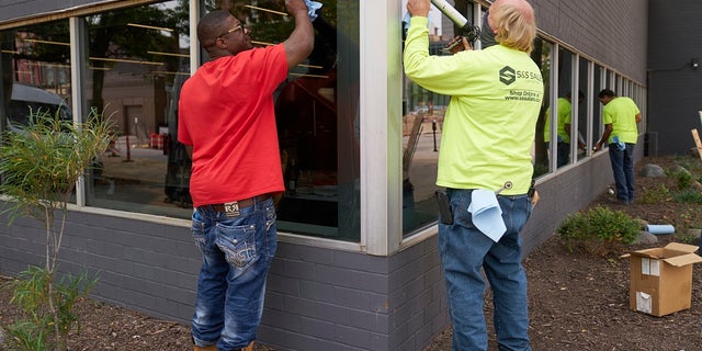 Workers replace windows smashed in May at a business in downtown Omaha, Neb., on Wednesday, one day after a grand jury decided to charge a white business owner who fatally shot Black James Scurlock during civil unrest in downtown Omaha this spring with manslaughter and other charges. (AP Photo/Nati Harnik)