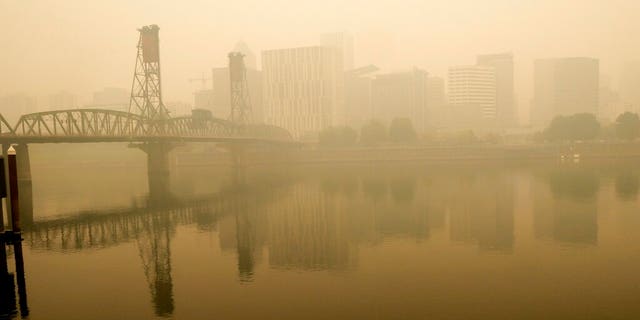 In this photo provided by Don Ryan, heavy smoke from wildfires envelops the Willamette Bridge and downtown Portland, Ore., Sept. 16. Dangerously dirty air spewing from the West Coast wildfires is seeping into homes and businesses, sneaking into cars through air conditioning vents and preventing people already shut away by the coronavirus pandemic from enjoying a walk or trip to the park. (Don Ryan via AP)
