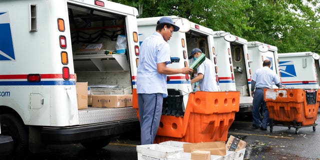 Οι μεταφορείς επιστολών φορτώνουν φορτηγά αλληλογραφίας για παραδόσεις σε εγκατάσταση ταχυδρομικής υπηρεσίας των ΗΠΑ στο McLean, Va. (AP Photo / J. Scott Applewhite)