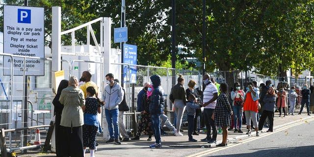 People queue up outside a coronavirus testing centre offering walk-in appointments in north London, Friday Sept. 18, 2020. (Kirsty O'Connor/PA via AP)