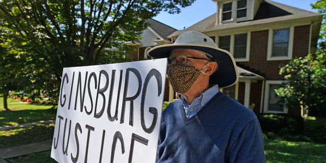 A protester stands outside the house of Senate Majority Leader Mitch McConnell, R-Ky., in Louisville, Ky., Saturday, Sept. 19, 2020. McConnell vowed on Friday night, hours after the death of Supreme Court Justice Ruth Bader Ginsburg to call a vote for whomever President Donald Trump nominated as her replacement. (AP Photo/Timothy D. Easley)