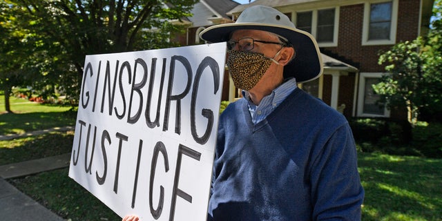 A protester stands outside the house of Senate Majority Leader Mitch McConnell, R-Ky., in Louisville, Ky., Saturday, Sept. 19, 2020. McConnell vowed on Friday night, hours after the death of Supreme Court Justice Ruth Bader Ginsburg to call a vote for whomever President Donald Trump nominated as her replacement. (AP Photo/Timothy D. Easley)