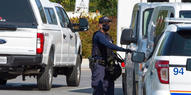 A Royal Canadian Mounted Police officer walks outside of an apartment complex Monday, Sept. 21, 2020, in St-Hubert, Quebec, during a raid in connection with an envelope containing the poison ricin, which was addressed to the White House.