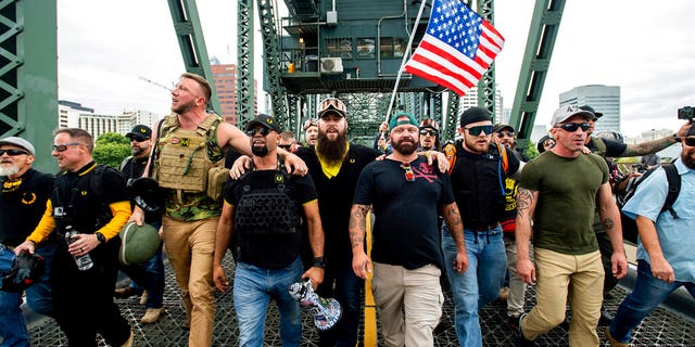 Members of the Proud Boys and other right-wing demonstrators march across the Hawthorne Bridge during a rally in Portland, Ore. (AP Photo/Noah Berger, File)