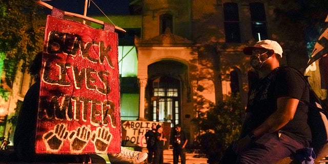 Protesters spend time in a church lot, Friday, Sept. 25, 2020, in Louisville. Breonna Taylor's family demanded Friday that Kentucky authorities release all body camera footage, police files and the transcripts of the grand jury hearings that led to no charges against police officers who killed the Black woman during a March drug raid at her apartment. (AP Photo/Darron Cummings)