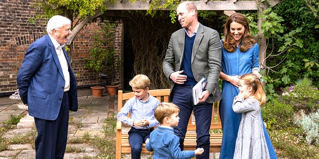 Prince William, center, and Kate Middleton, the Duchess of Cambridge, react with naturalist David Attenborough, left, with their children, Prince George, seated; Princess Charlotte, right; and Prince Louis, foreground, in the gardens of Kensington Palace in London.
