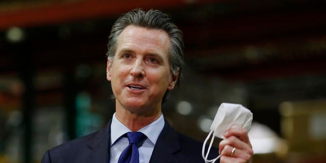 In this June 26, 2020 file photo, Gov. Gavin Newsom holds a face mask as he urges people to wear them to fight the spread of the coronavirus during a news conference in Rancho Cordova, Calif. (AP Photo/Rich Pedroncelli, Pool, File)