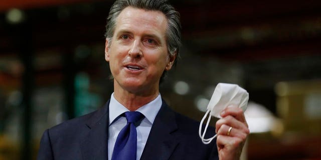 Gov. Gavin Newsom holds a face mask as he urges people to wear them to fight the spread of the coronavirus during a news conference in Rancho Cordova, Calif.