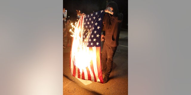 A protester burns an American flag while rallying at the Mark O. Hatfield United States Courthouse on Saturday, Sept. 26, 2020, in Portland, Ore. The rally came as Portland has seen nearly nightly protests since the police killing of George Floyd in late May. (G3 Box News Photo/Allison Dinner)