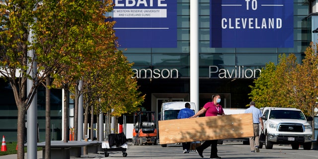 A woman carries a table while setting up outside of the Health Education Campus of Case Western Reserve University ahead of the first presidential debate between Republican candidate President Donald Trump and Democratic candidate former Vice President Joe Biden, Sunday, Sept. 27, 2020, in Cleveland. (AP Photo/Julio Cortez)