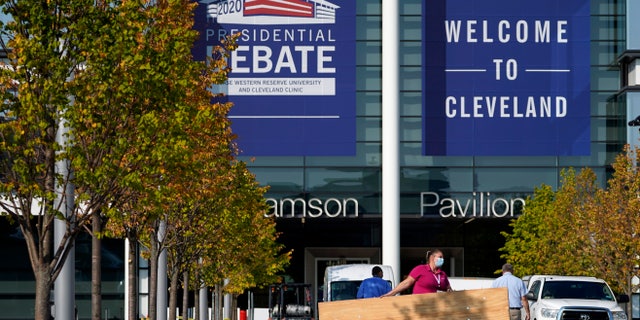 A woman carries a table while setting up outside of the Health Education Campus of Case Western Reserve University ahead of the first presidential debate between Republican candidate President Donald Trump and Democratic candidate former Vice President Joe Biden, Sunday, Sept. 27, 2020, in Cleveland. (AP Photo/Julio Cortez)