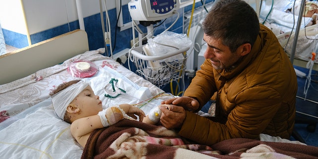 A man speaks with his child, wounded during shelling, in Stepanakert, the self-proclaimed Republic of Nagorno-Karabakh, Azerbaijan, Monday, Sept. 28, 2020. Fighting between Armenian and Azerbaijani forces over the disputed separatist region of Nagorno-Karabakh continued on Monday morning after erupting the day before, with both sides blaming each other for resuming the attacks. (Areg Balayan/PAN Photo via AP)